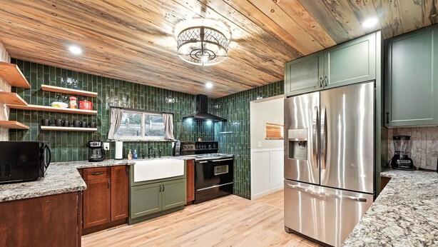 A kitchen with wooden cabinets, a stainless steel refrigerator, and a granite countertop. - Mountain Serenity Retreat - Larkspur Retreat (Larkspur)