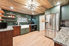 Una cocina con armarios de madera, un refrigerador de acero inoxidable y una encimera de granito.
