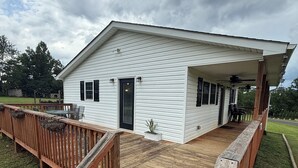 A white single-story house with a wooden deck and a covered porch.