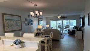 Un grand espace de vie comprenant une table à manger, des chaises, un canapé et un ventilateur de plafond.