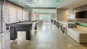 Mesa de bilhar, área de bar e assentos em um lounge moderno.