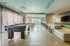 Een pooltafel, bar en zithoek in een moderne lounge.
