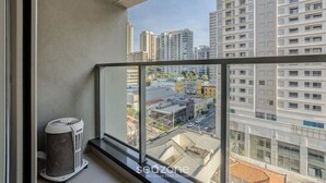 Uma varanda com vista para o horizonte urbano, um cesto de lixo e um peitoril de janela.