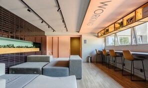 Un espacio de trabajo moderno con una mesa larga, taburetes tipo bar y una zona de estar con bancos acolchados.