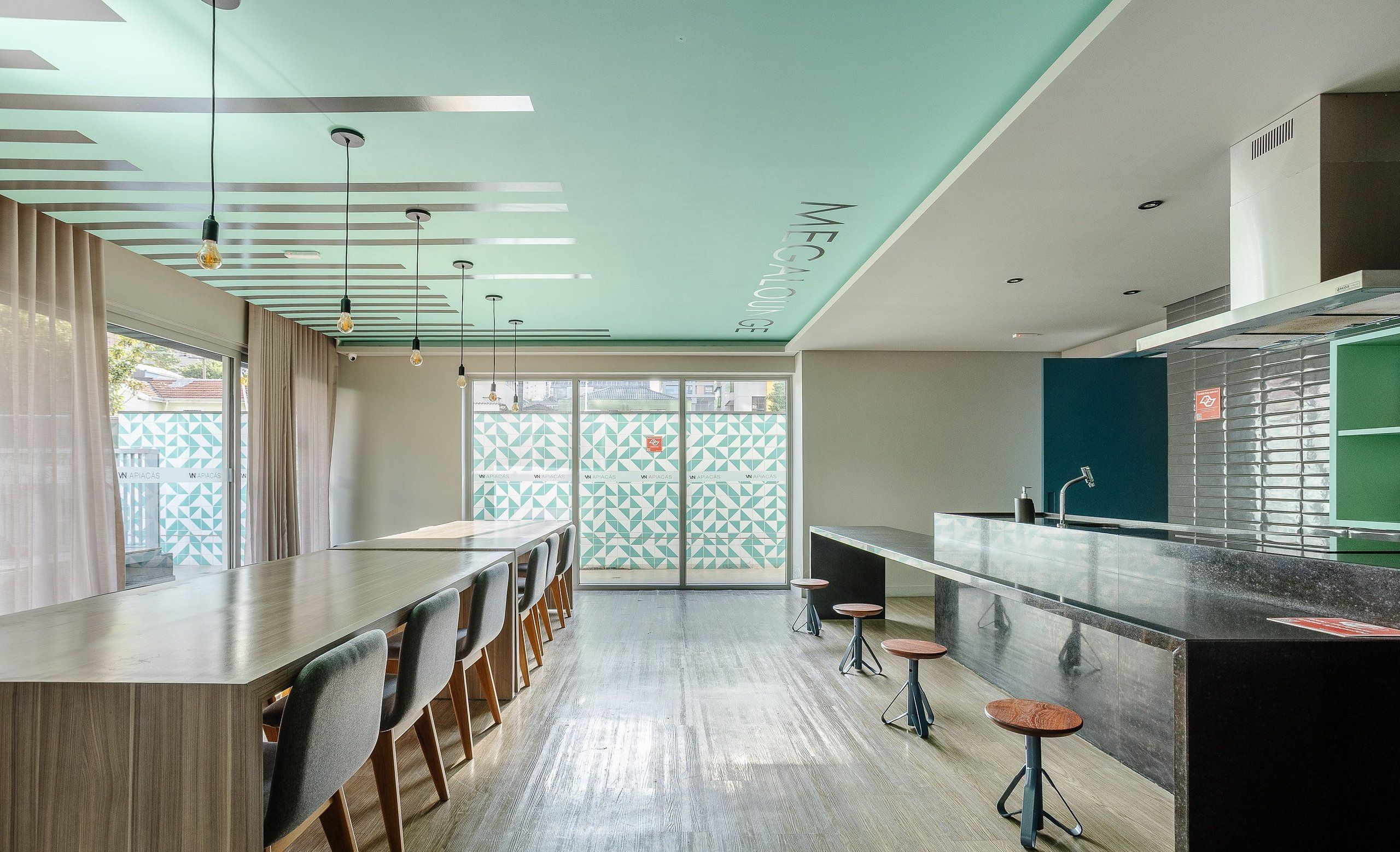 Una cucina moderna con un lungo bancone, sgabelli e una vista attraverso una porta decorata.