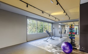 Une salle de sport équipée de matériel d’exercice, dotée de grandes fenêtres et d’un miroir.