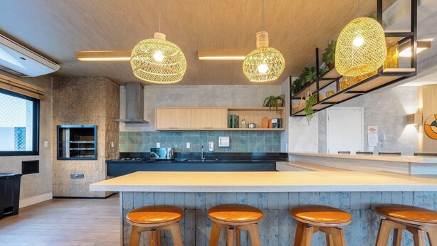 Une cuisine moderne dotée d’un îlot central, de tabourets de bar, de luminaires suspendus en osier et offrant une vue sur l’extérieur.