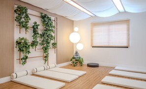 A room with a wooden floor, a wall-mounted plant, a meditation bench, a small statue, and a window with blinds. - Beautiful Units at Viva Benx Vila Olimpia - VBX (São Paulo)