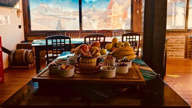 A dining table with various food items and a large window with a mountain view. - Marvelous 8-bedroom catered ski chalet in Bansko with Total Chalets (Bansko)