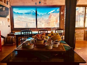 A dining table with various food items and a large window with a mountain view. - Marvelous 8-bedroom catered ski chalet in Bansko with Total Chalets (Bansko)