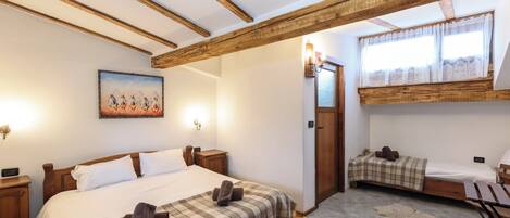 A hotel room with a large bed, a smaller bed, a desk, and a window with curtains.