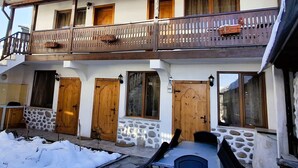 A two-story building with a balcony, stone facade, and wooden doors. - Marvelous 8-bedroom catered ski chalet in Bansko with Total Chalets (Bansko)