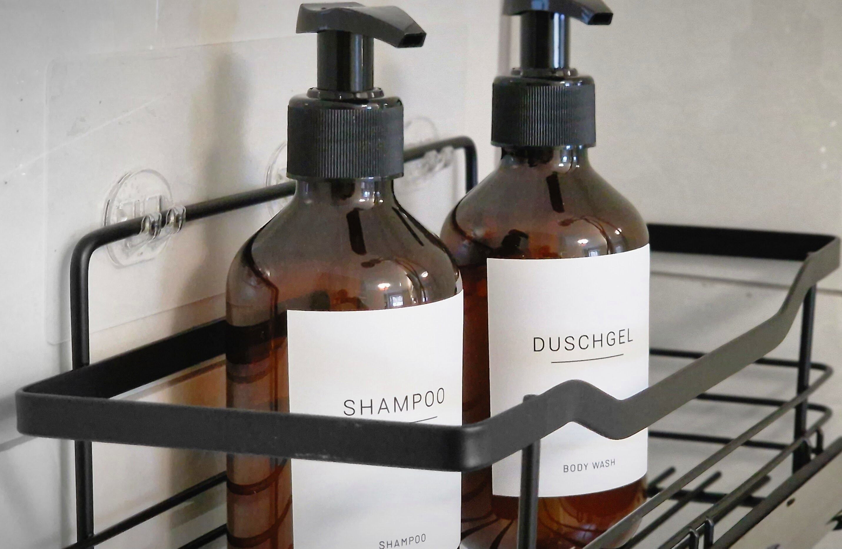Dois frascos de shampoo e hidratante corporal em uma prateleira de metal.