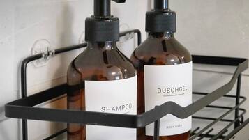 Dois frascos de shampoo e hidratante corporal em uma prateleira de metal.
