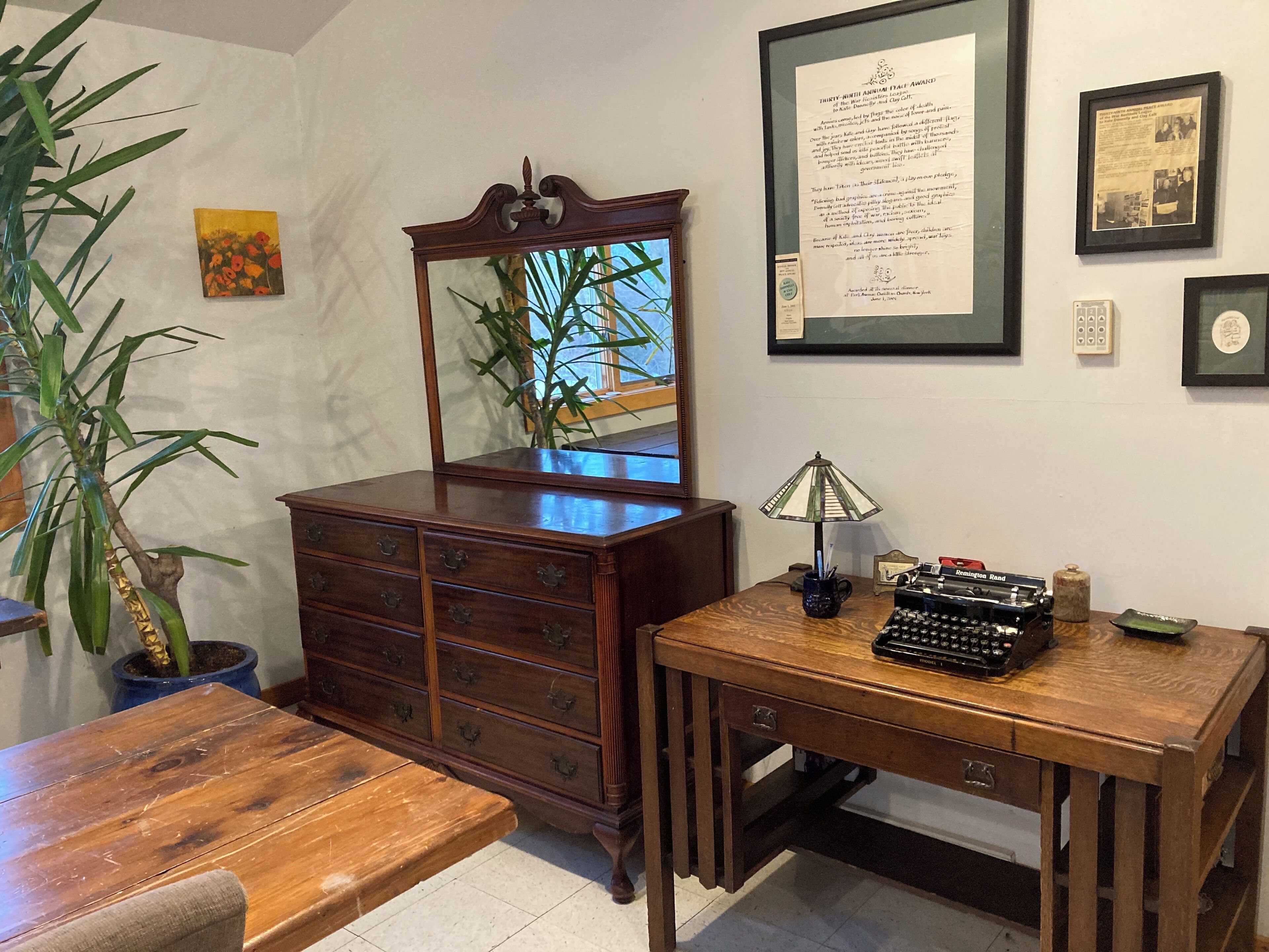 Un bureau en bois, une machine à écrire, un miroir et un cadre contenant une récompense accroché au mur.