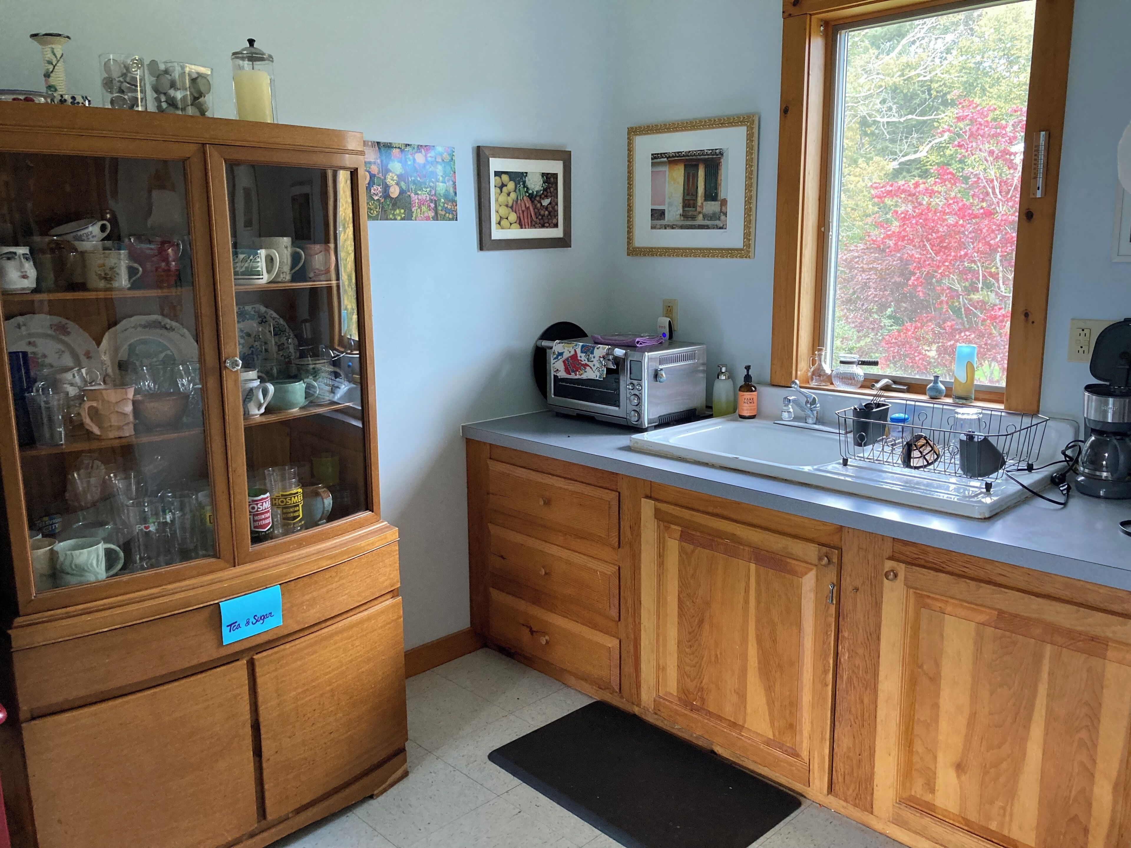 A kitchen with wooden cabinets, a built-in microwave, and a window with a view of trees.