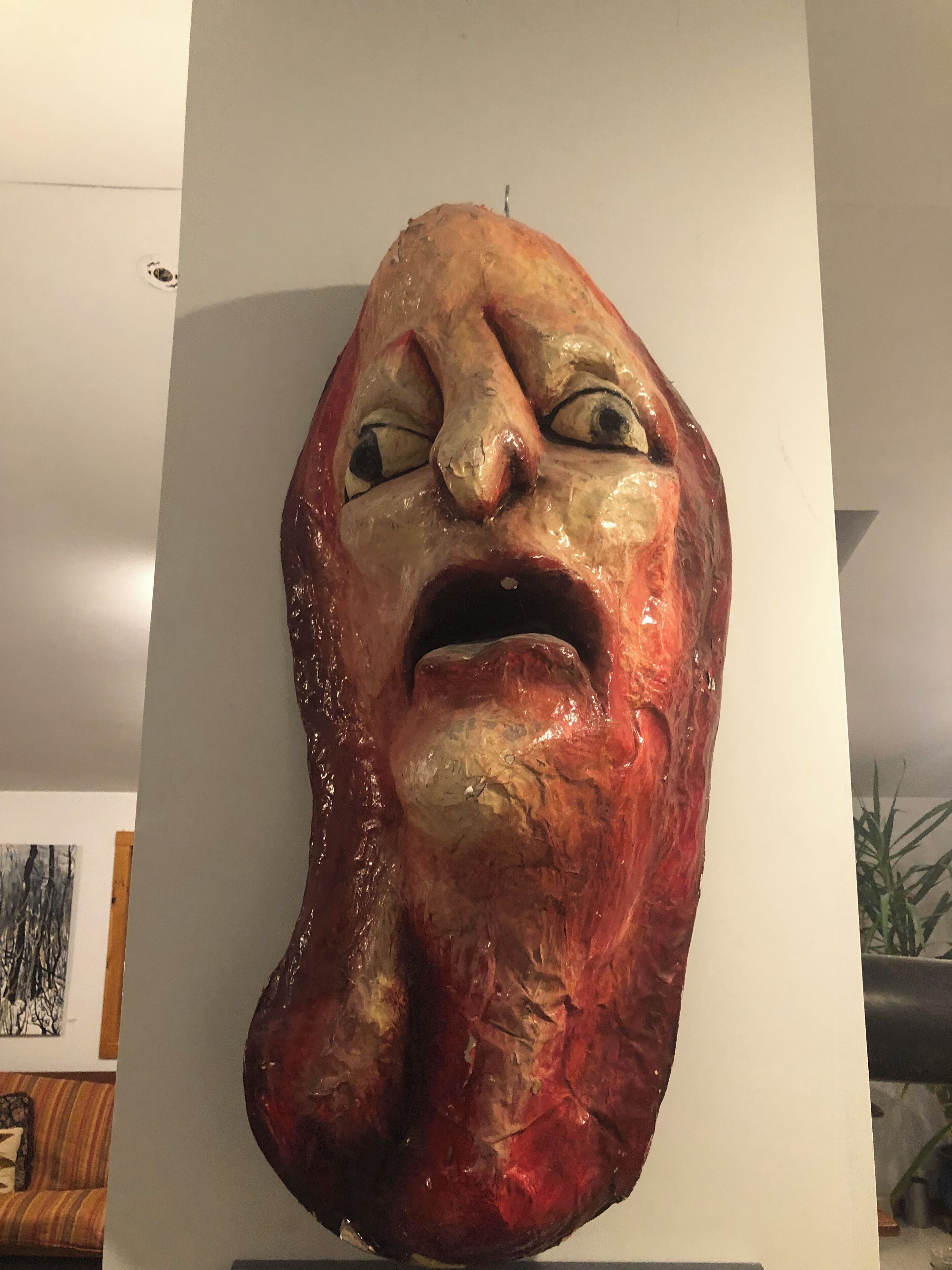 A large, abstract sculpture with a rough texture and a mix of red and beige colors.