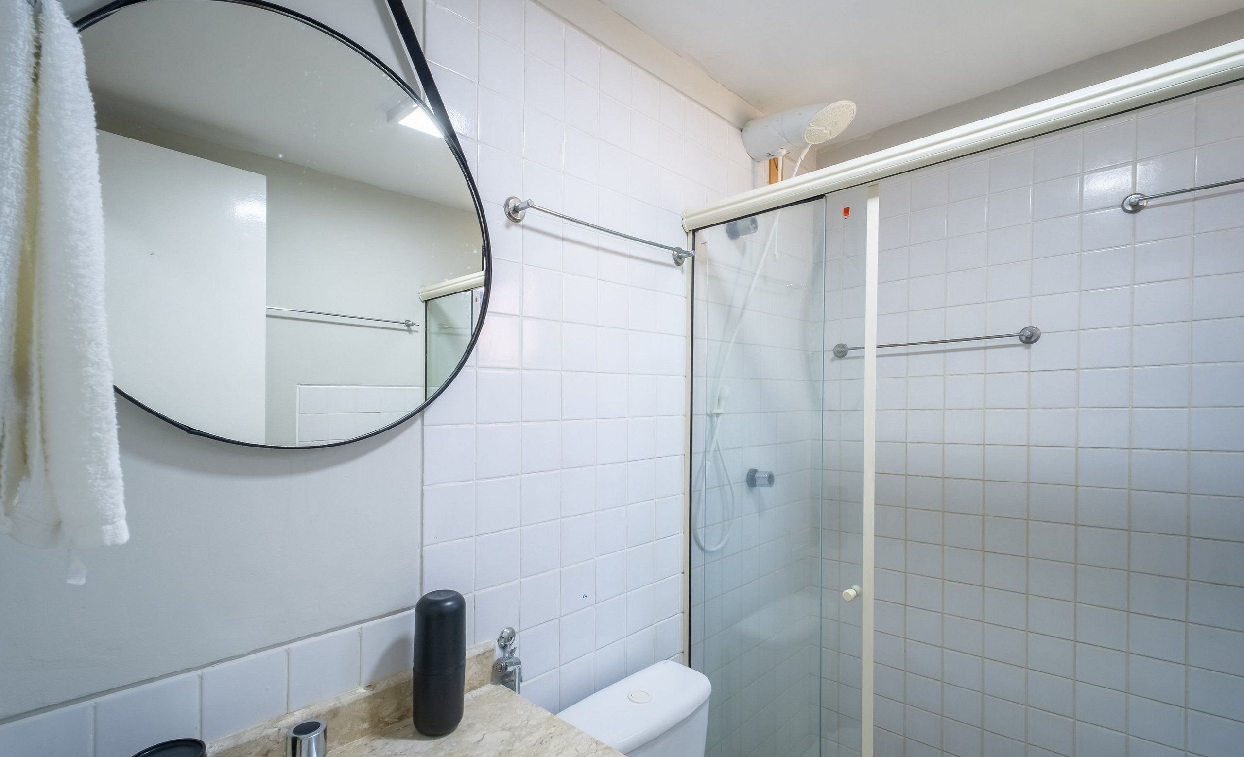 A bathroom with a toilet, a sink, a mirror, and a glass-enclosed shower area.