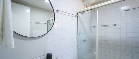 A bathroom with a toilet, a sink, a mirror, and a glass-enclosed shower area.