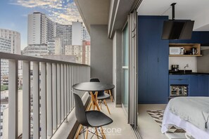 A modern bedroom with a balcony, a dining area, and a kitchenette.