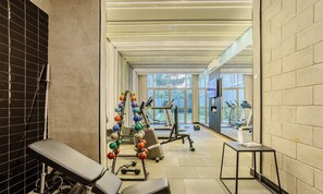 A gym with exercise equipment, a bench, and a small table.