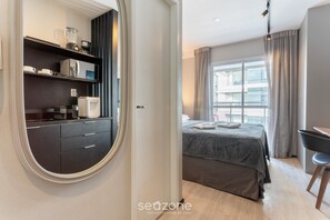 A modern bedroom with a bed, a desk, and a built-in wardrobe. - Modern Studio With Pool in Sao Paulo You1203 (São Paulo)