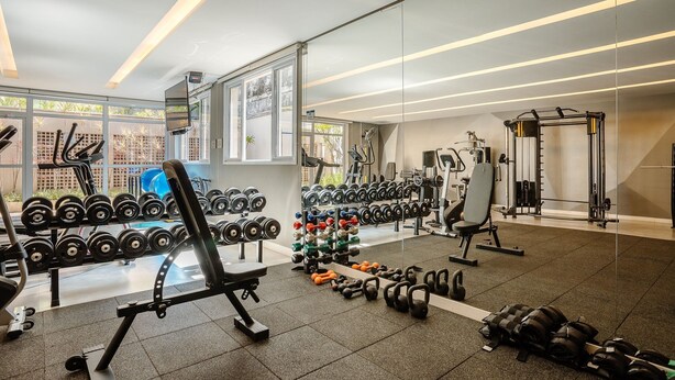 A modern gym with various weightlifting equipment, including dumbbells and benches, and large windows providing natural light. - Modern Studio With Pool in Sao Paulo You1203 (São Paulo)