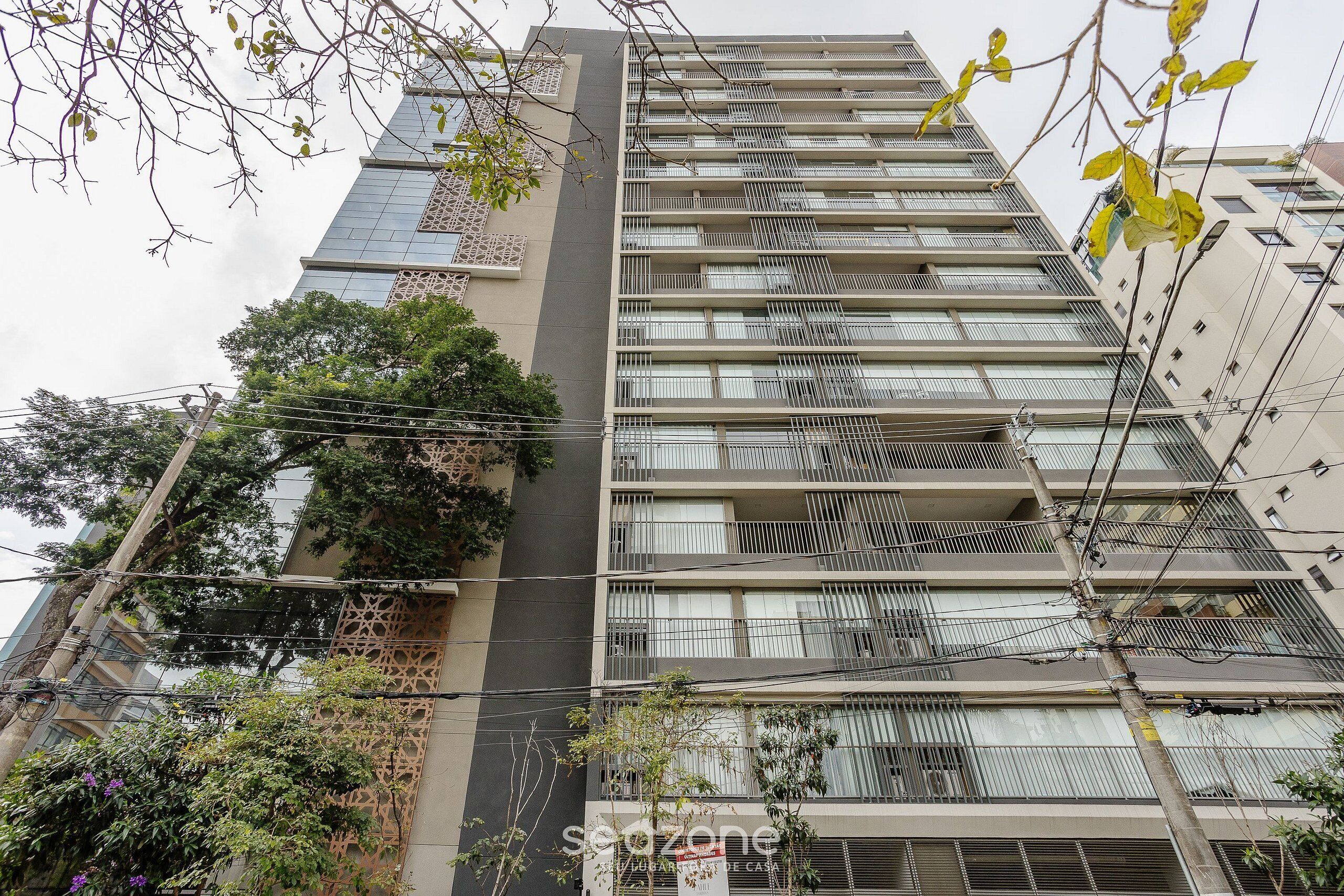 A multi-story building with balconies, a visible power line, and some greenery.