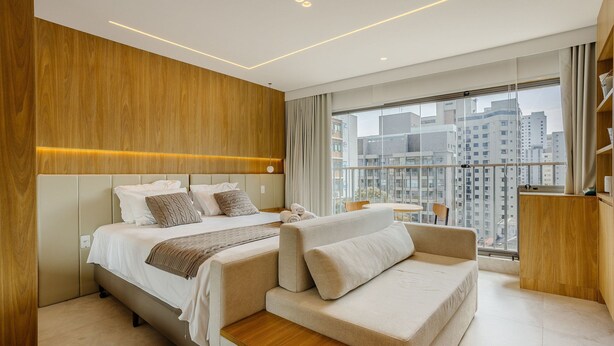 A modern hotel room with a large bed, a sofa, and a balcony with a city view. - Studio in Condominium With Pool in Paraiso Zah0811 (São Paulo)