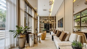 A modern interior with a sofa, potted plants, and a kitchen area. - Studio in Condominium With Pool in Paraiso Zah0811 (São Paulo)