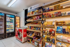 Una tienda de comestibles con estantes llenos de aperitivos, bebidas y artículos del hogar.