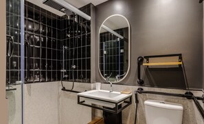Un baño moderno con cabina de ducha de vidrio, un lavamanos blanco, un espejo y un inodoro.