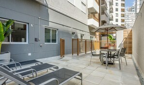 A courtyard with outdoor seating, a table with chairs, and a large umbrella. - Apts in Perdizes, Near the Allianz Parque - WEL (São Paulo)