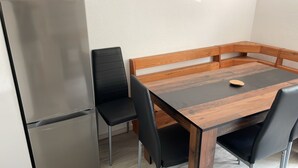 A modern kitchen with a stainless steel refrigerator, black chairs, and a wooden dining table with a bench. - WatzmannEG (Augsburg)