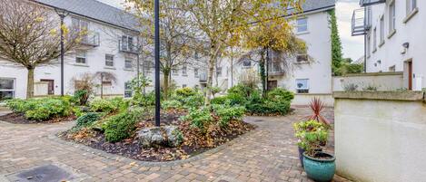 A courtyard with a paved walkway, surrounded by white buildings with balconies and windows.