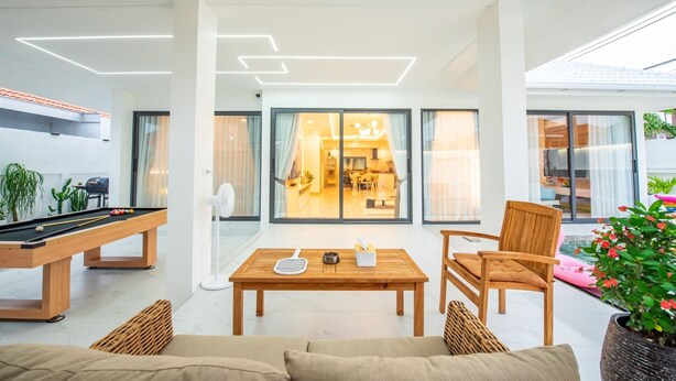 A modern living room with a pool table, a sofa, and a dining area.