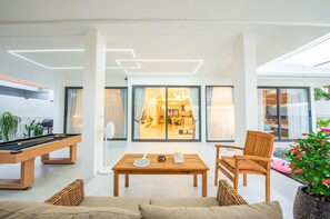 Moderni olohuone, jossa on biljardipöytä, sohva ja ruokailutila.