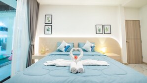 A hotel room with a bed, a nightstand, a lamp, and a view of the outside.