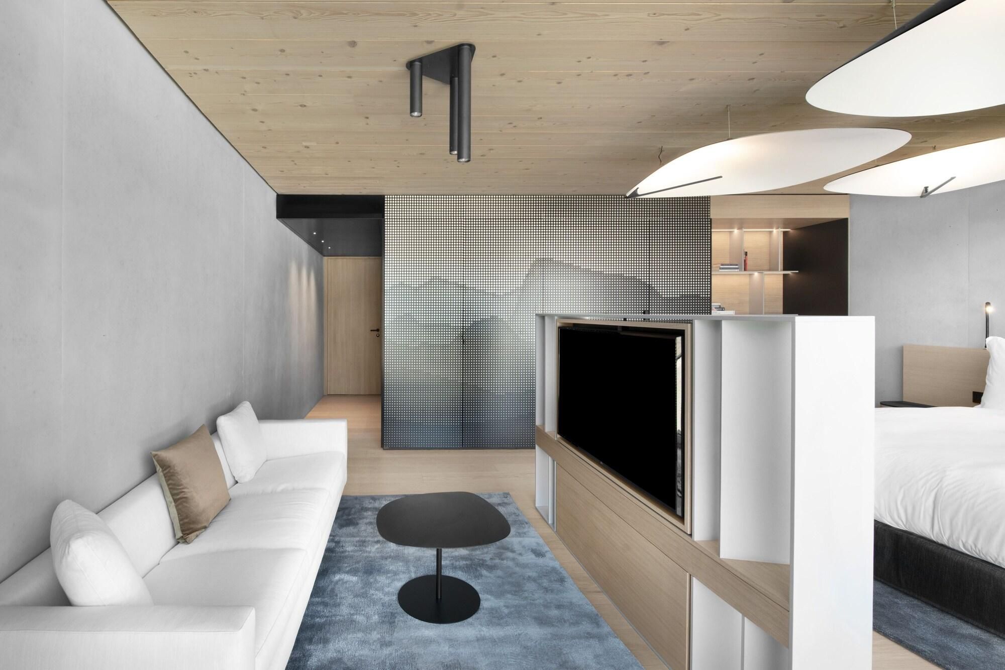 Quarto de hotel moderno com sofá, televisão e cama.