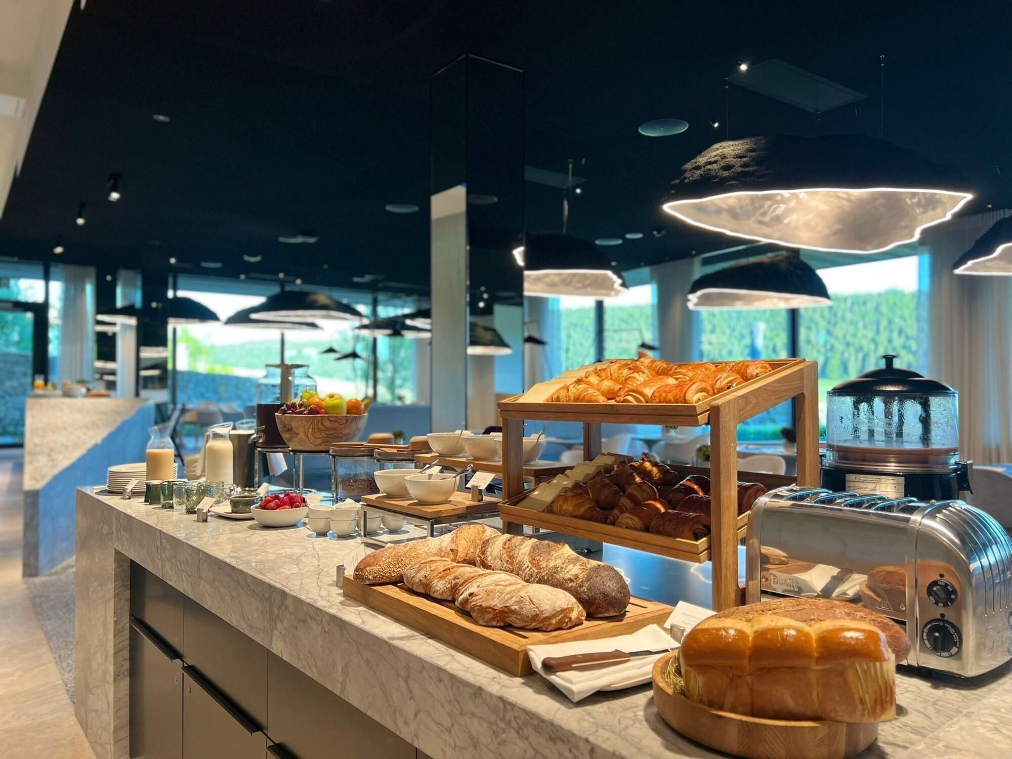A breakfast buffet with various breads, pastries, and a coffee machine.