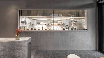 A modern kitchen with a large window, marble countertops, and a minimalist chair.