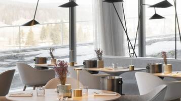 A modern dining area with tables, chairs, and pendant lights.