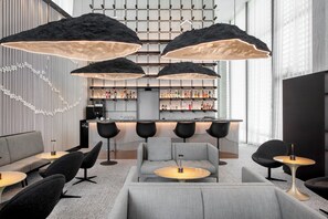 A modern lounge area with sofas, round tables, and pendant lighting.