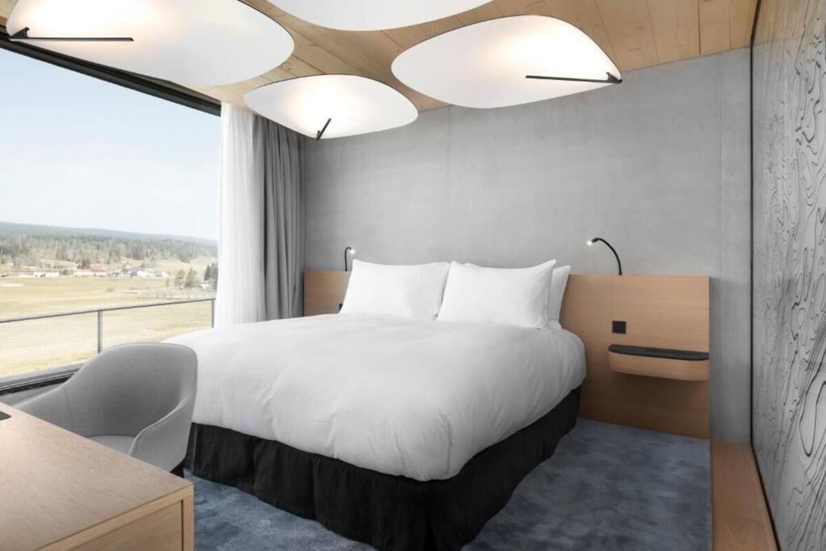 Une chambre d’hôtel moderne avec un grand lit, un bureau et une vue sur un paysage.