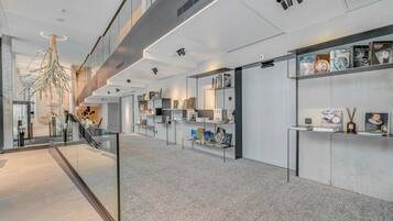 A modern interior with a glass railing, bookshelves, and a unique tree-like light fixture.