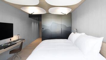 Una moderna camera d'albergo con un letto, una scrivania, una sedia e una grande televisione.