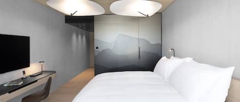 Ein modernes Hotelzimmer mit Bett, Schreibtisch, Stuhl und einem großen Fernseher.