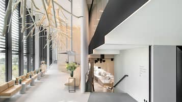 A modern interior with a long corridor, seating areas, and a staircase leading to a dining area.