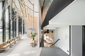 Un intérieur moderne avec un long couloir, des espaces de détente et un escalier menant à une salle à manger.