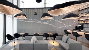 A modern lounge area with sofas, tables, and pendant lighting.